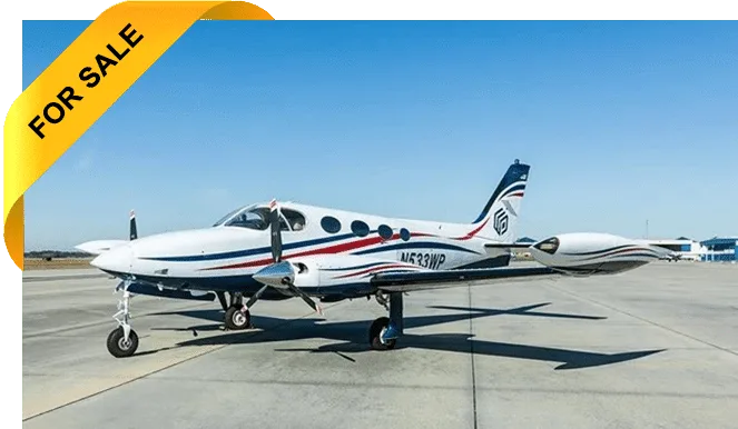 A white twin-engine turboprop aircraft with blue and red stripes and a tail logo is parked on an airfield under a clear blue sky.