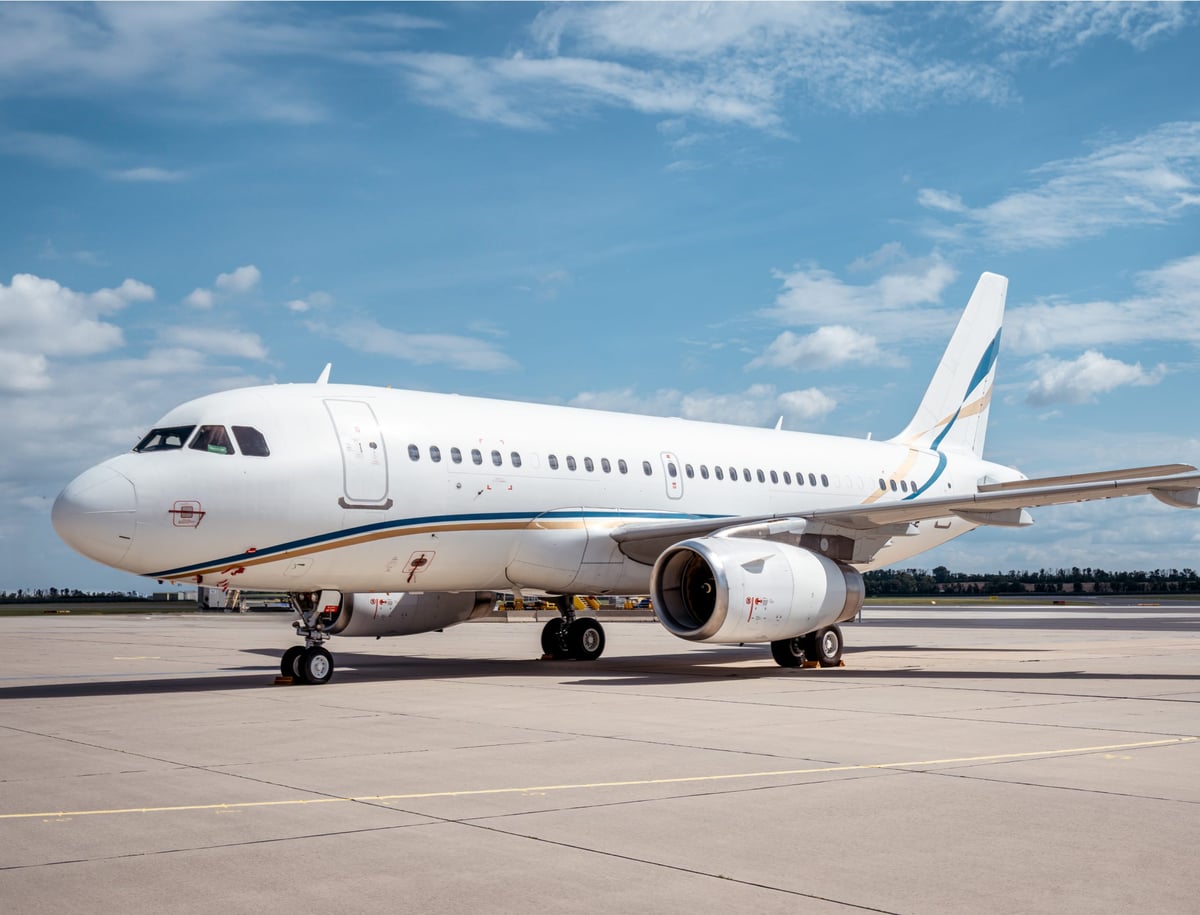 A white Airbus A319 aircraft parked on the tarmac.