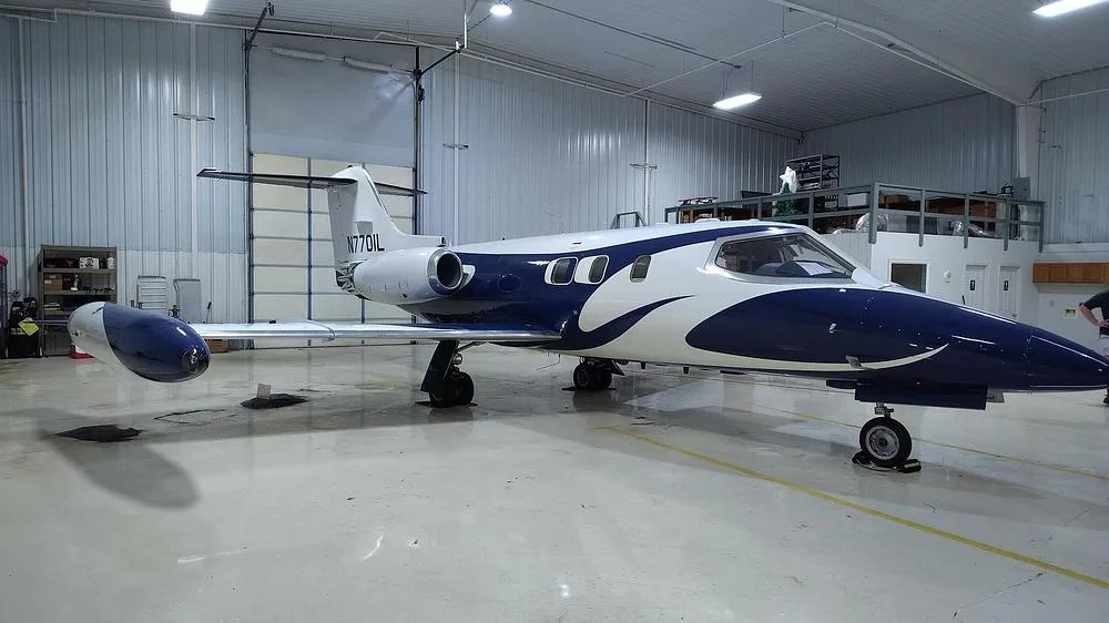A Learjet 35A in a blue and white paint scheme, viewed from the front-left, parked inside a hangar.
