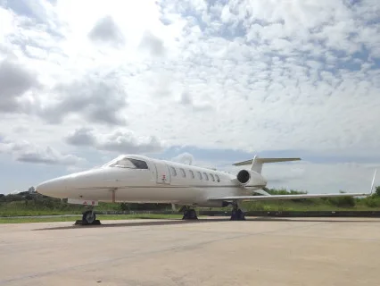 A Learjet sits on the tarmac under a cloudy sky.