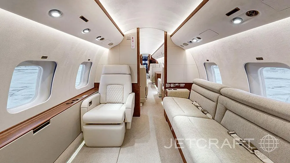The aircraft's interior cabin features a long cream-colored sofa and a single quilted leather seat.