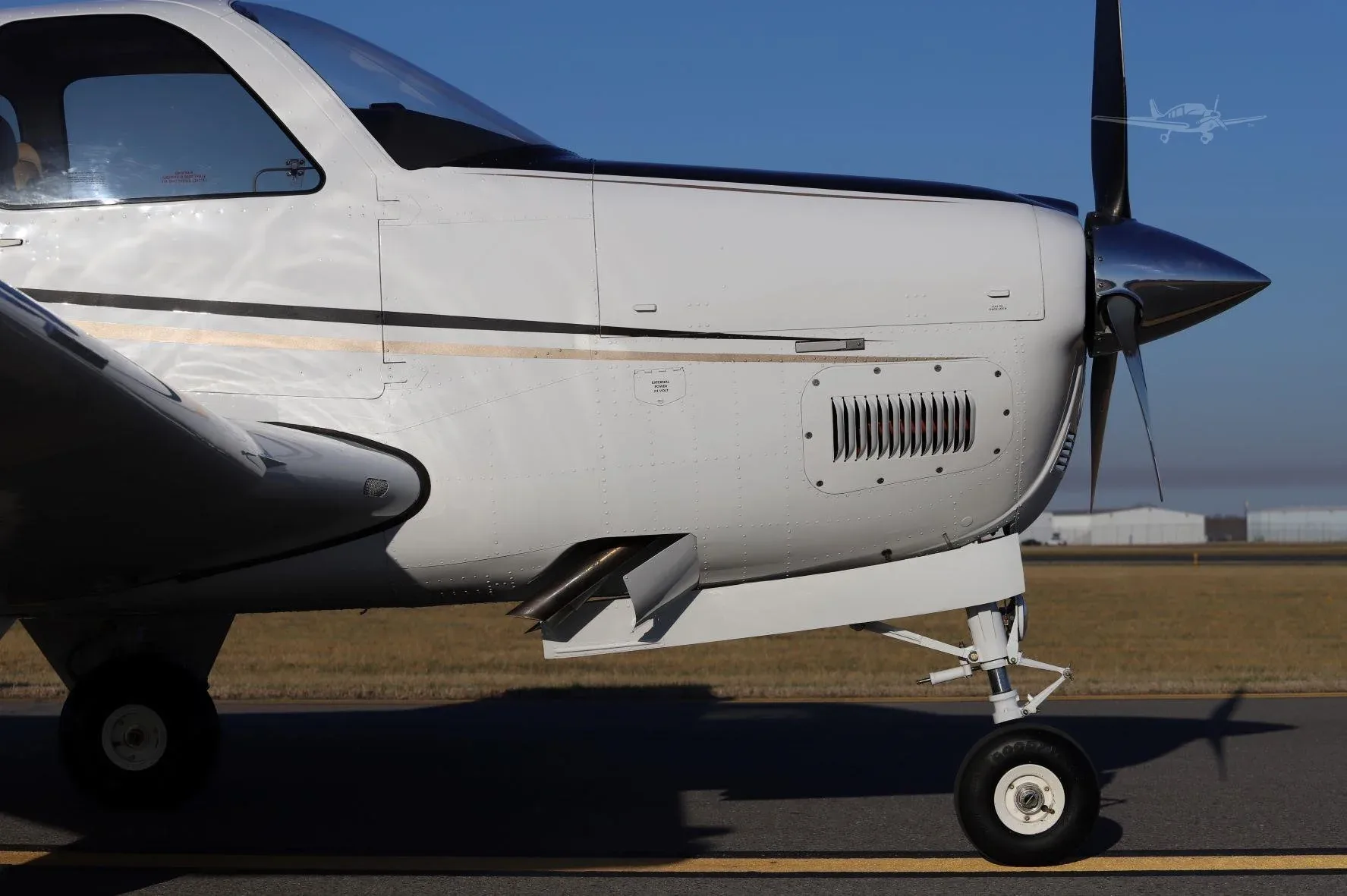 A close-up view of the engine cowling and propeller of a white Beechcraft Bonanza G36 on a runway.