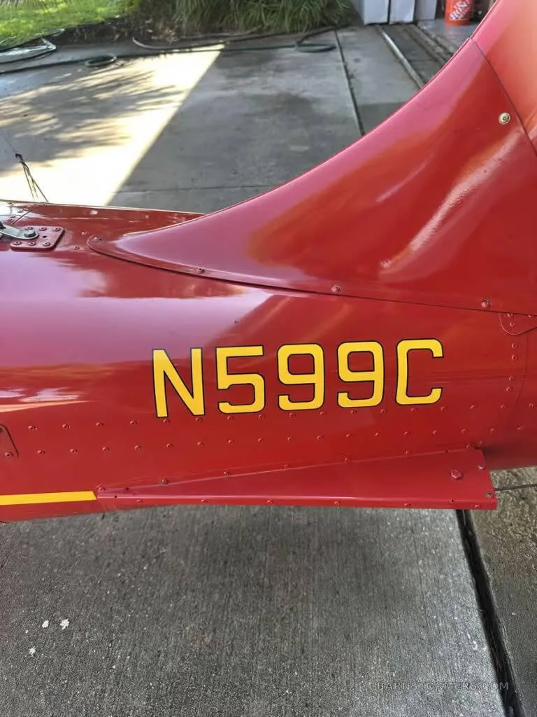 A close-up view of the red fuselage of an aircraft, showing the yellow registration number N599C.