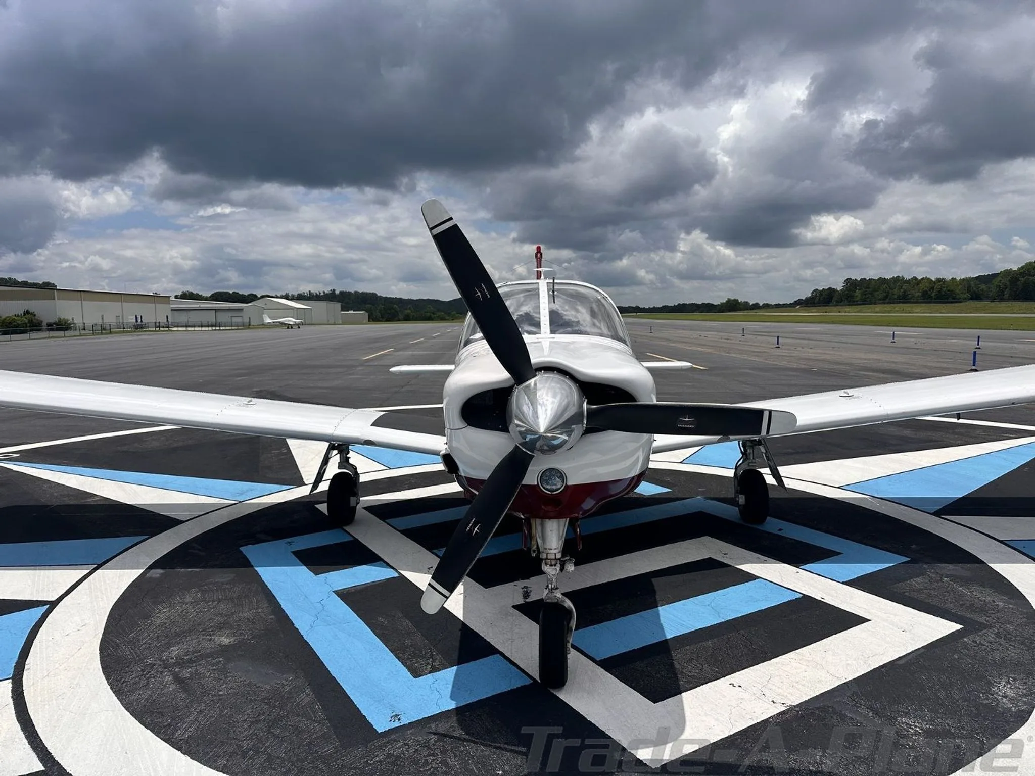A head-on view of the white and red aircraft N203BW with its propeller, parked on an airport runway.