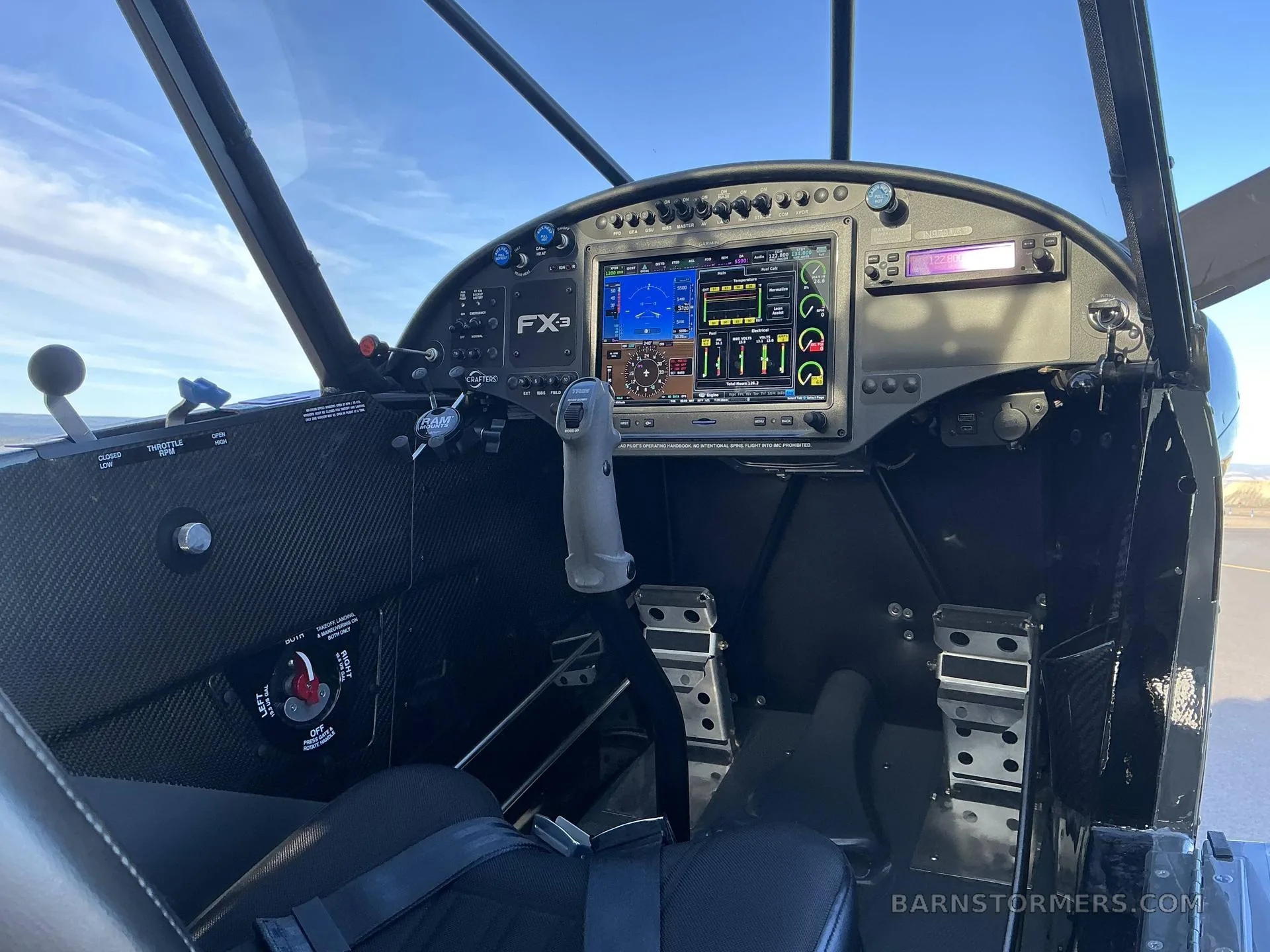 The cockpit of a Carbon Cub FX3, showing the digital instrument panel, stick, and rudder pedals.