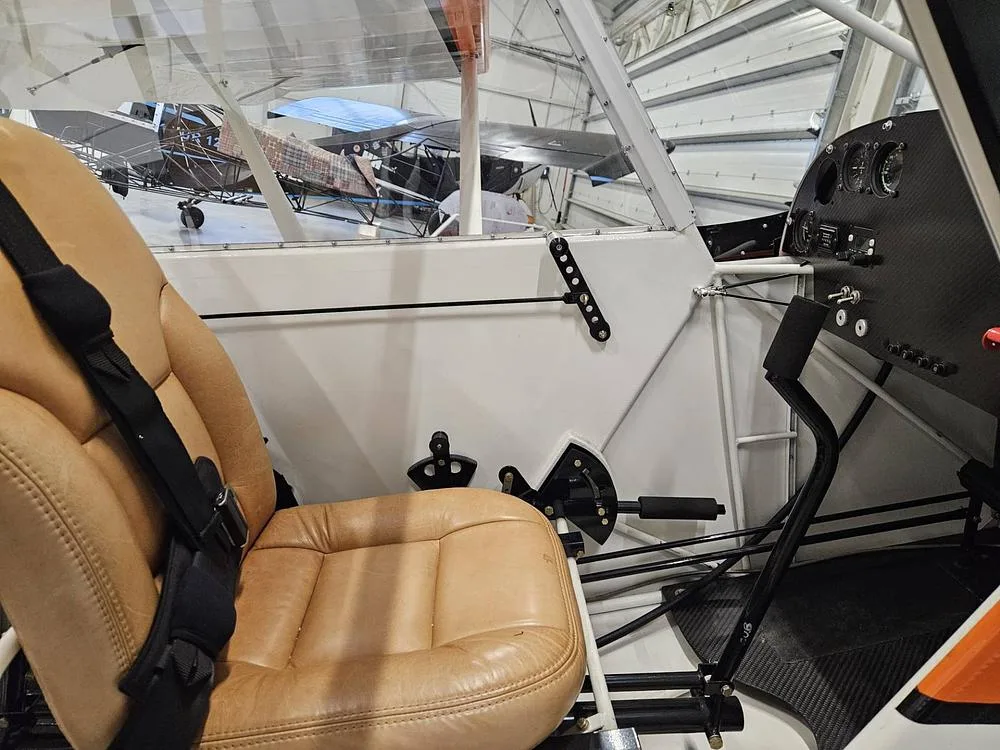 The tan pilot's seat and partial instrument panel of the aircraft, viewed from inside the cabin.