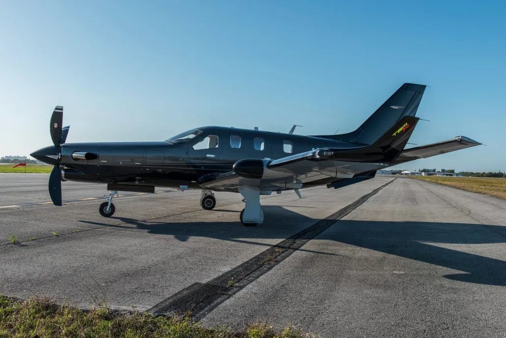 Side view of a dark gray turboprop aircraft on the runway.