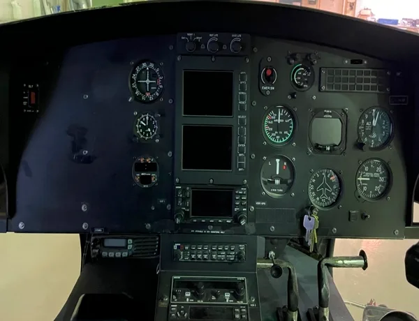 Helicopter cockpit instrument panel with various gauges and displays.