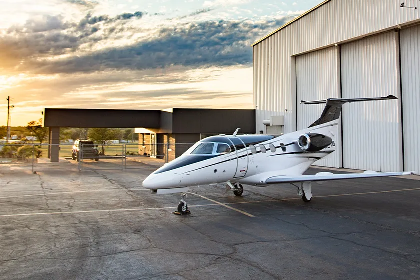 Cirrus Vision Jet with a black and white paint scheme parked outside a hangar at sunset.