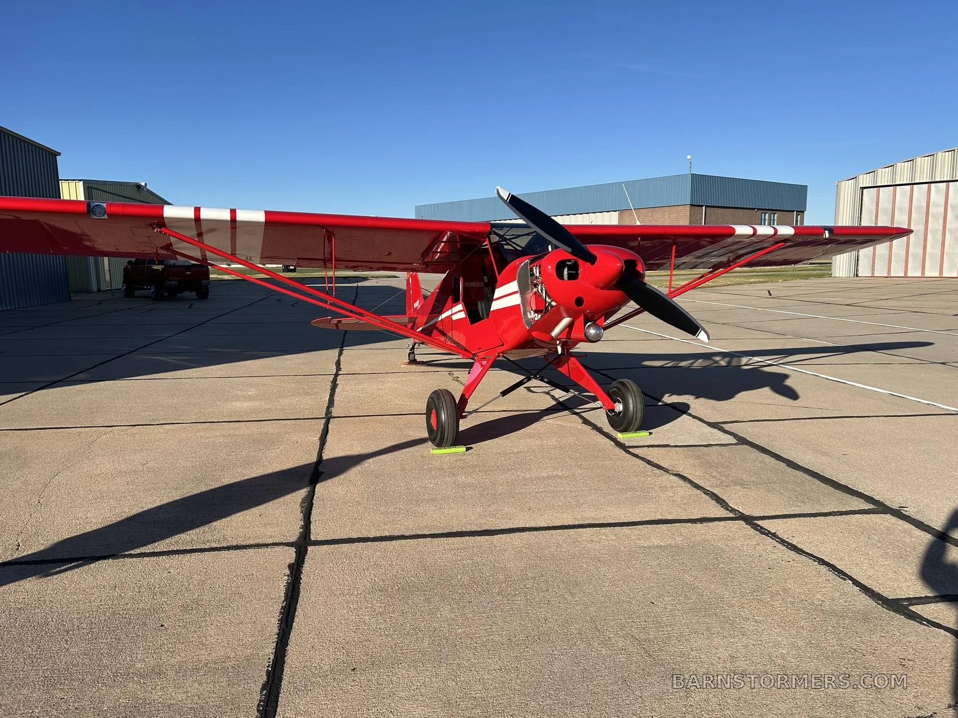 A red PA-18 Supercub positioned on the runway.