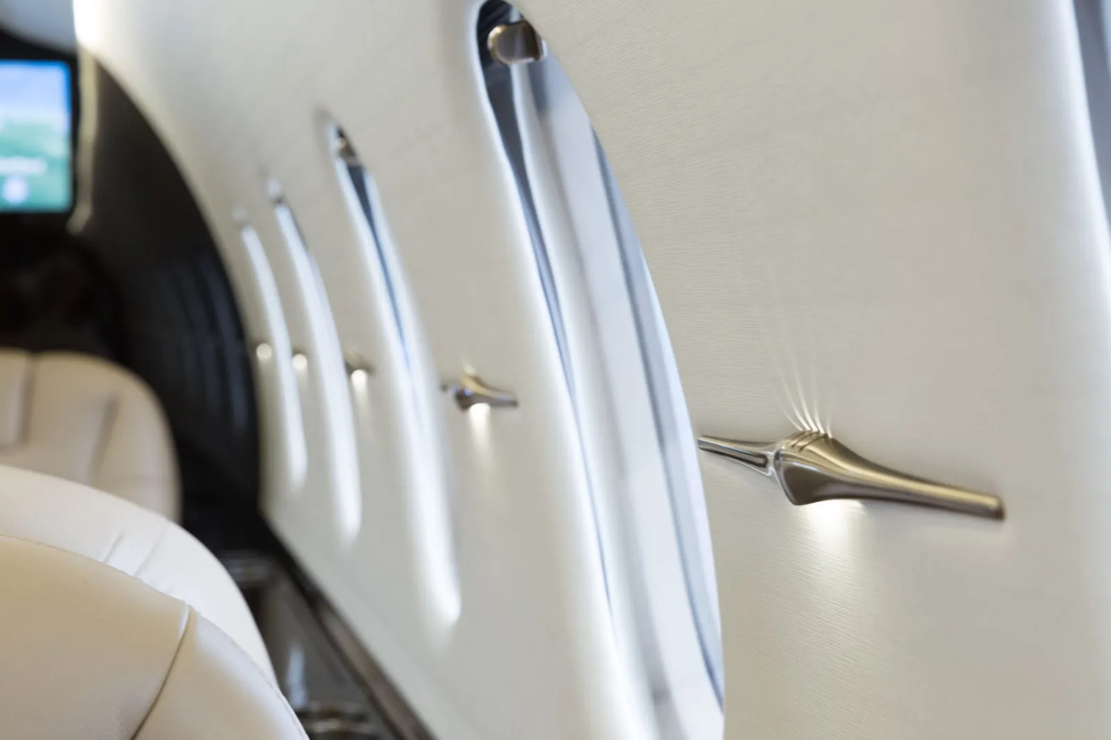 A close-up view of the aircraft's white cabin wall with multiple oval windows and elegant light fixtures.