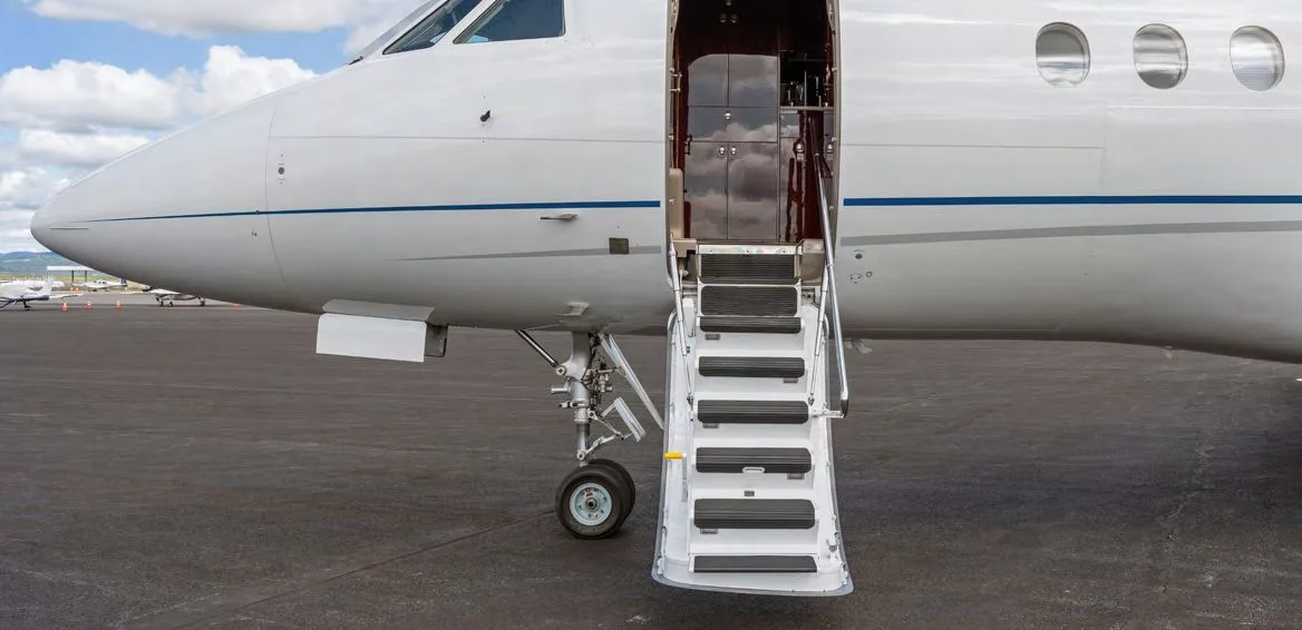 The open main entry door and integrated airstairs of a white business jet.