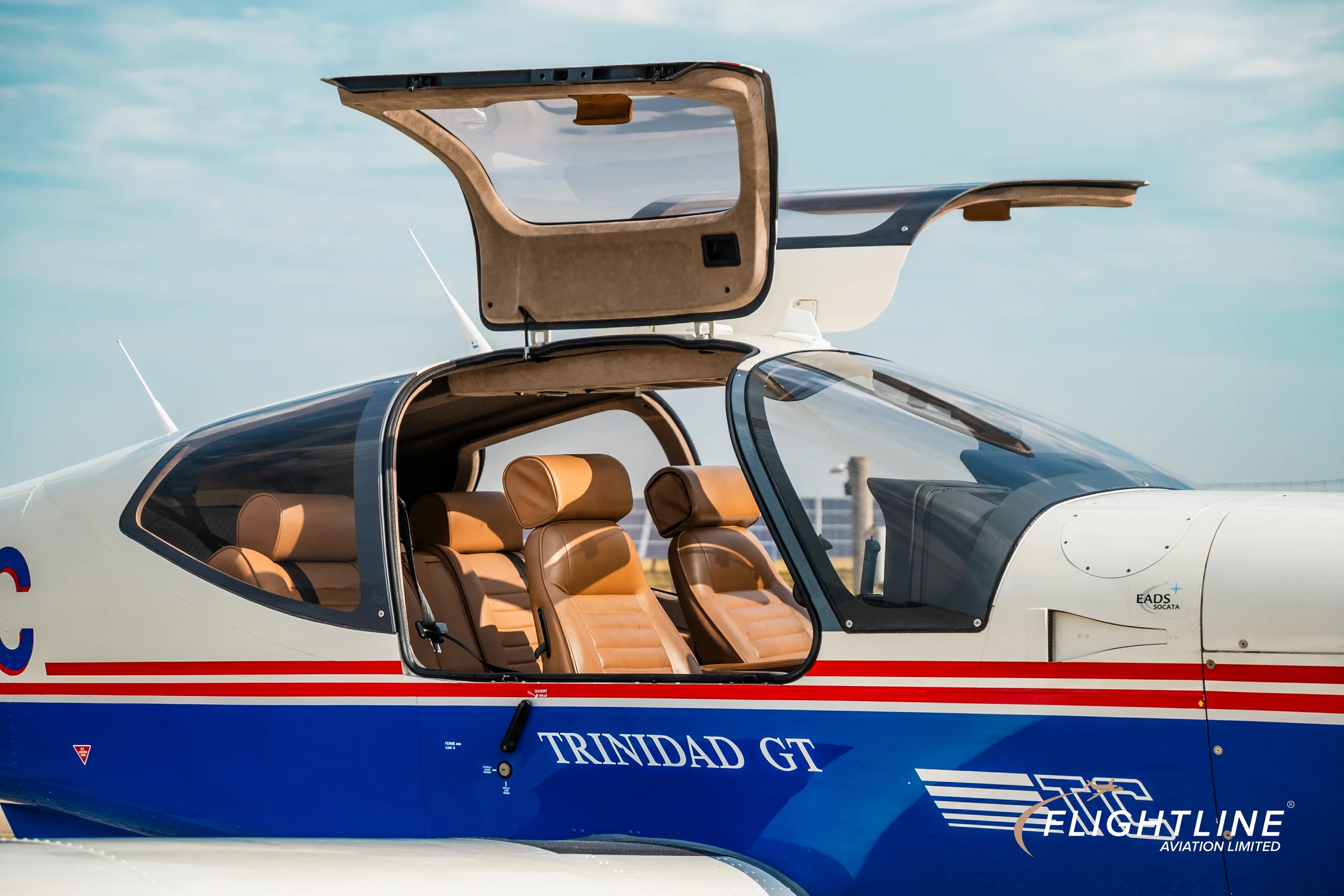 A close-up of the N377C Socata Trinidad GT's cabin with both doors open, revealing tan leather seats.
