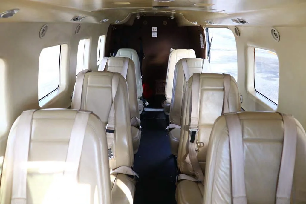 The interior cabin of an aircraft with multiple rows of light tan passenger seats.