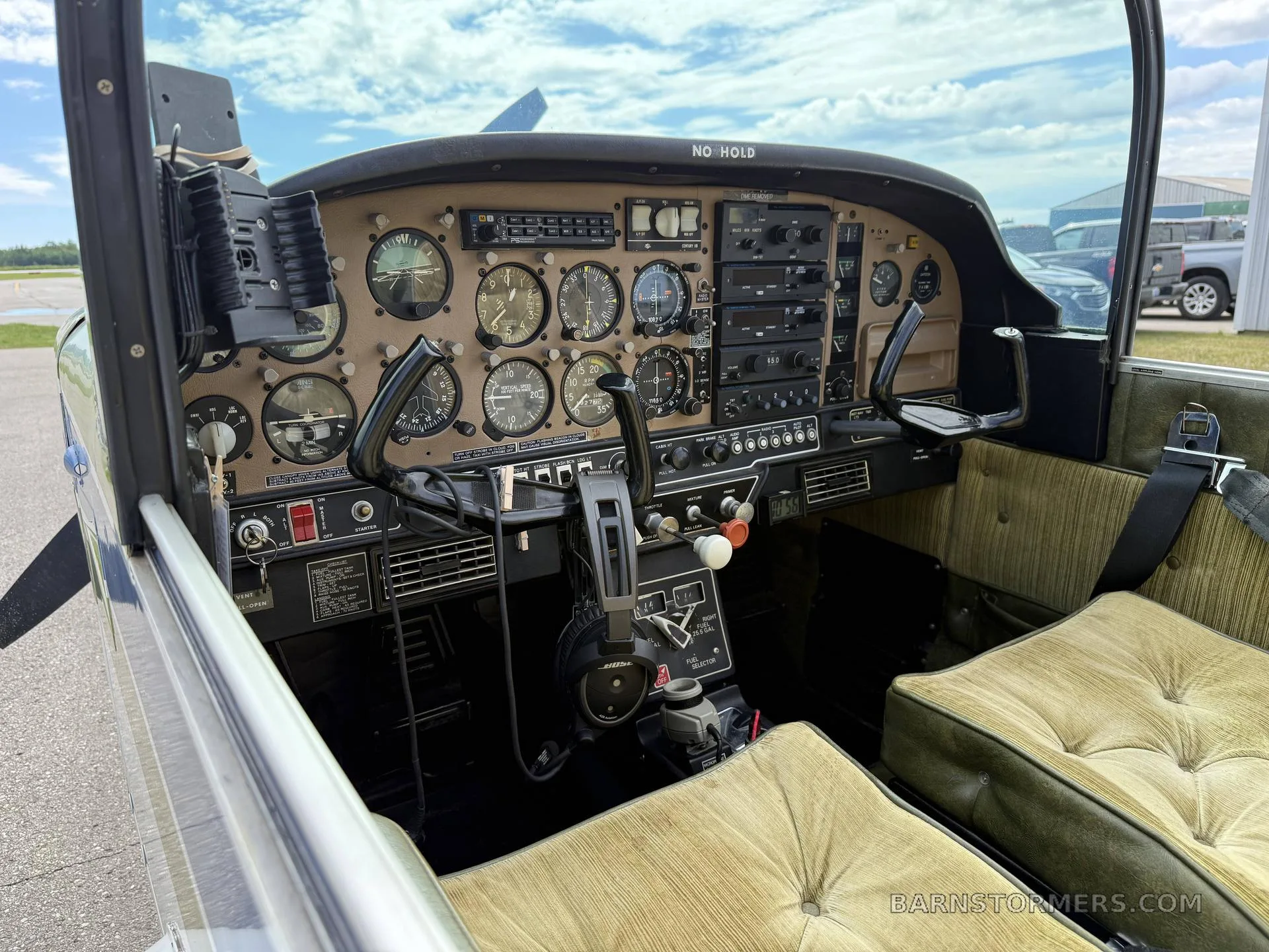 The cockpit of a Grumman American aircraft, showing the instrument panel, yokes, and green upholstered seats.