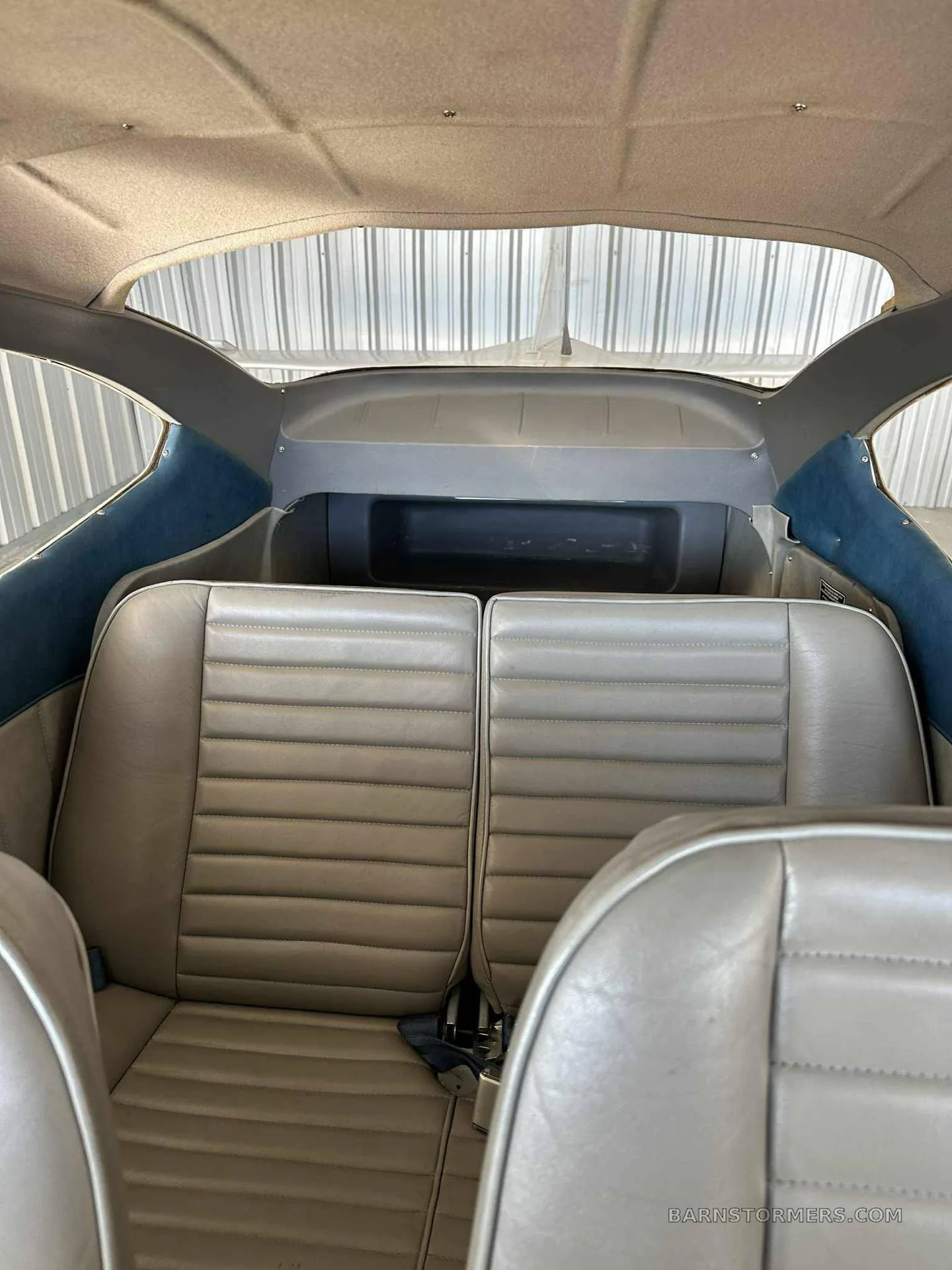 The light grey leather rear seats and interior cabin of a small aircraft, looking towards the tail.