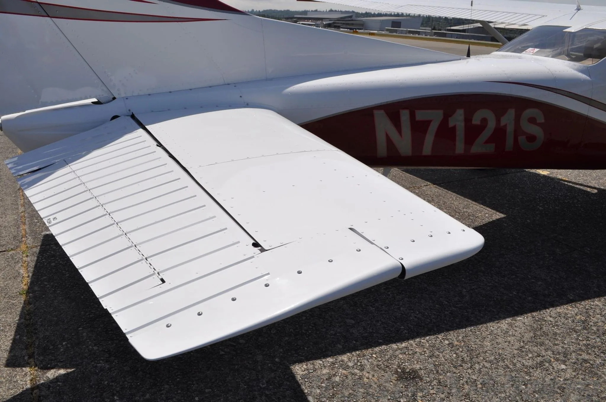 A close-up view of the white horizontal stabilizer and red tail section of the Cessna N7121S.