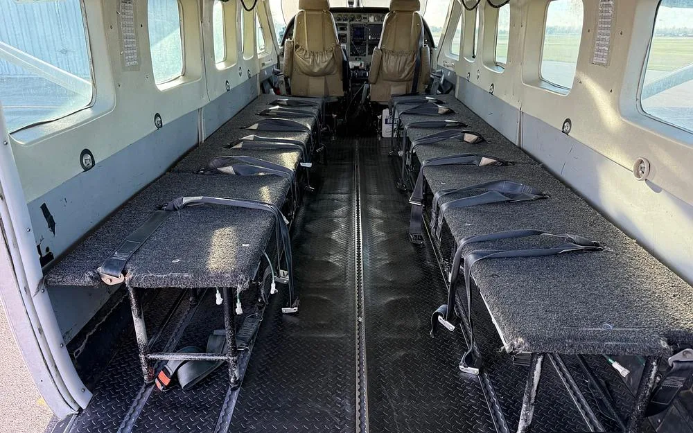 The aircraft's interior cabin features long benches along the sides, configured for skydiving.