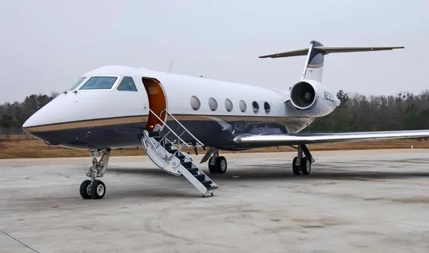 Interior of a private jet with leather seats and a wooden table.
