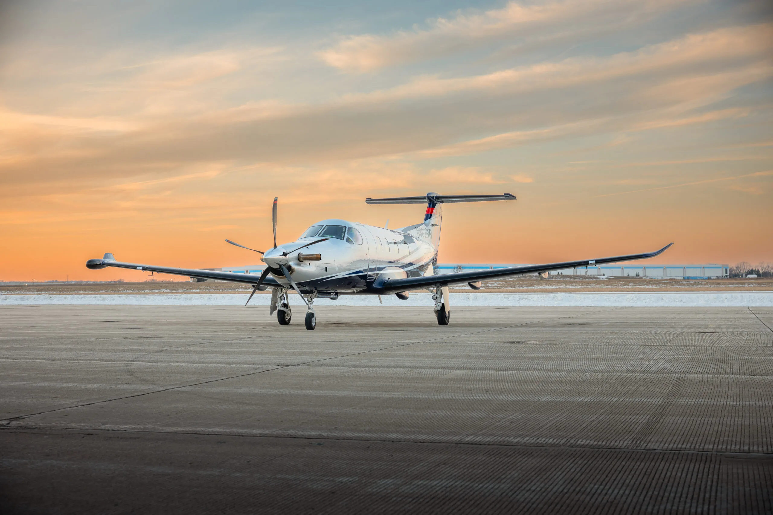 A silver and blue Pilatus PC-12 turboprop aircraft with registration N882RR on a tarmac under a cloudy sky.