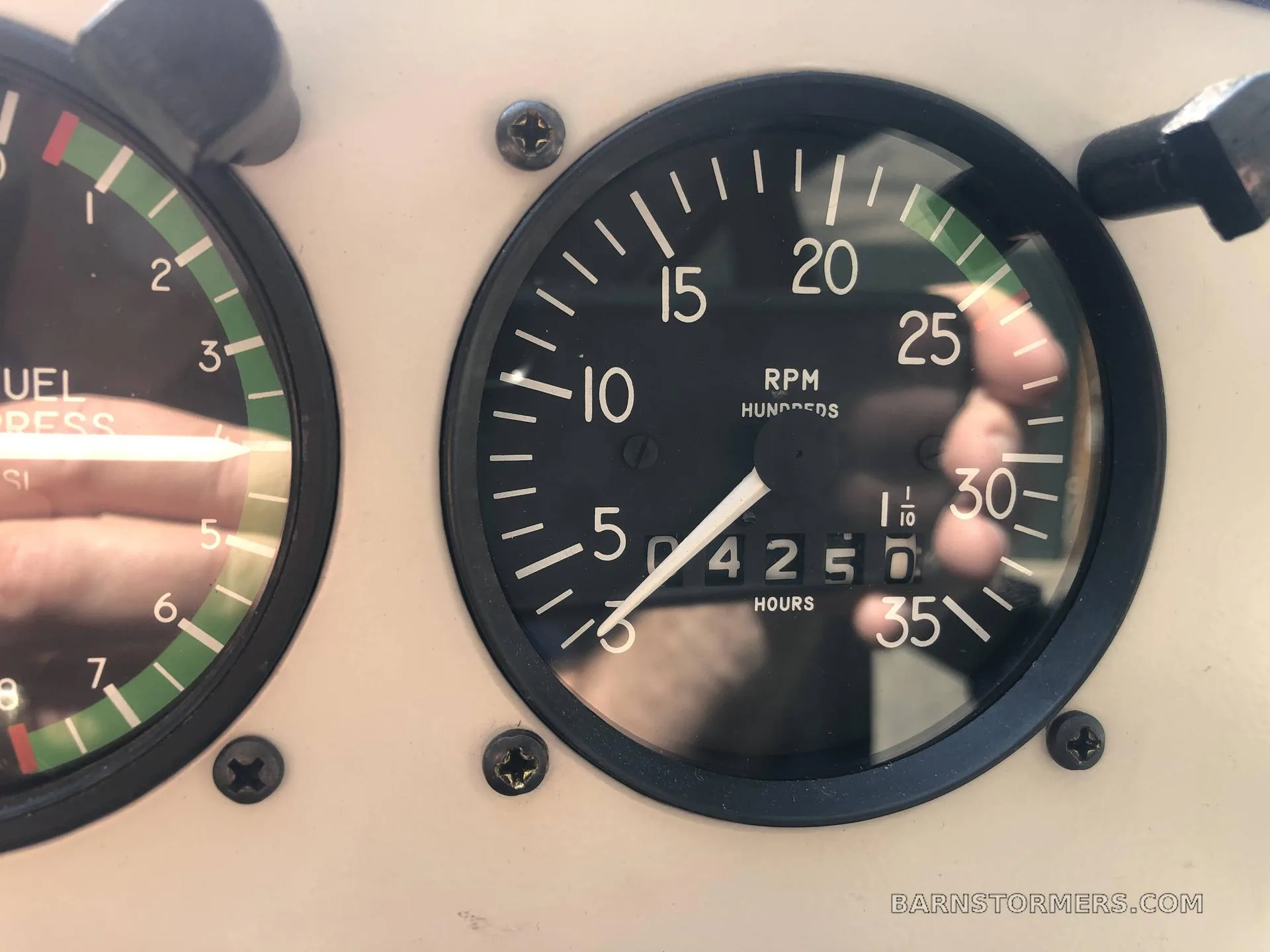 A close-up of an aircraft instrument showing RPM in hundreds and 425.0 hours.
