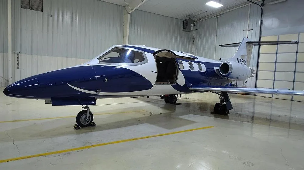 A Learjet 35A in a blue and white paint scheme, with its main door open, parked inside a hangar.