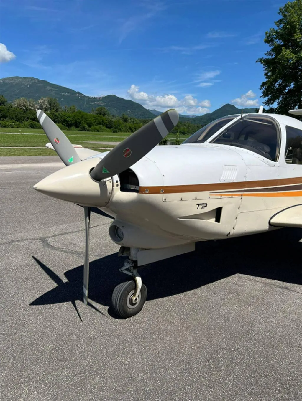 A close-up view of the propeller and nose of a white and brown Piper Arrow III.