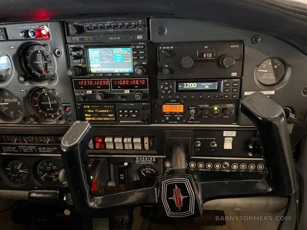 A detailed view of an aircraft cockpit's instrument panel, showing various gauges, radios, and a control yoke with an Oldsmobile-like logo.