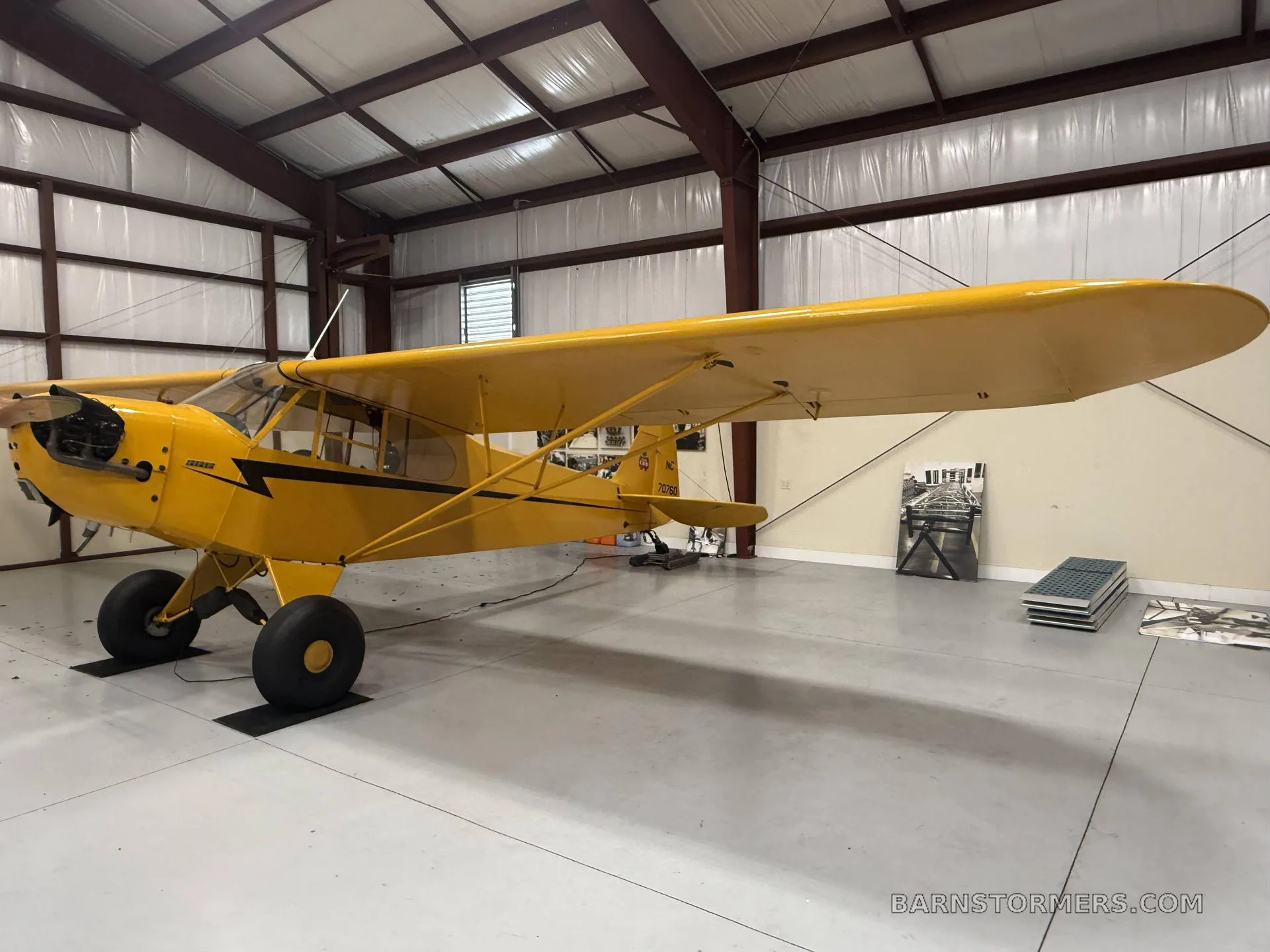 A yellow single-engine aircraft with large tires parked inside a hangar.
