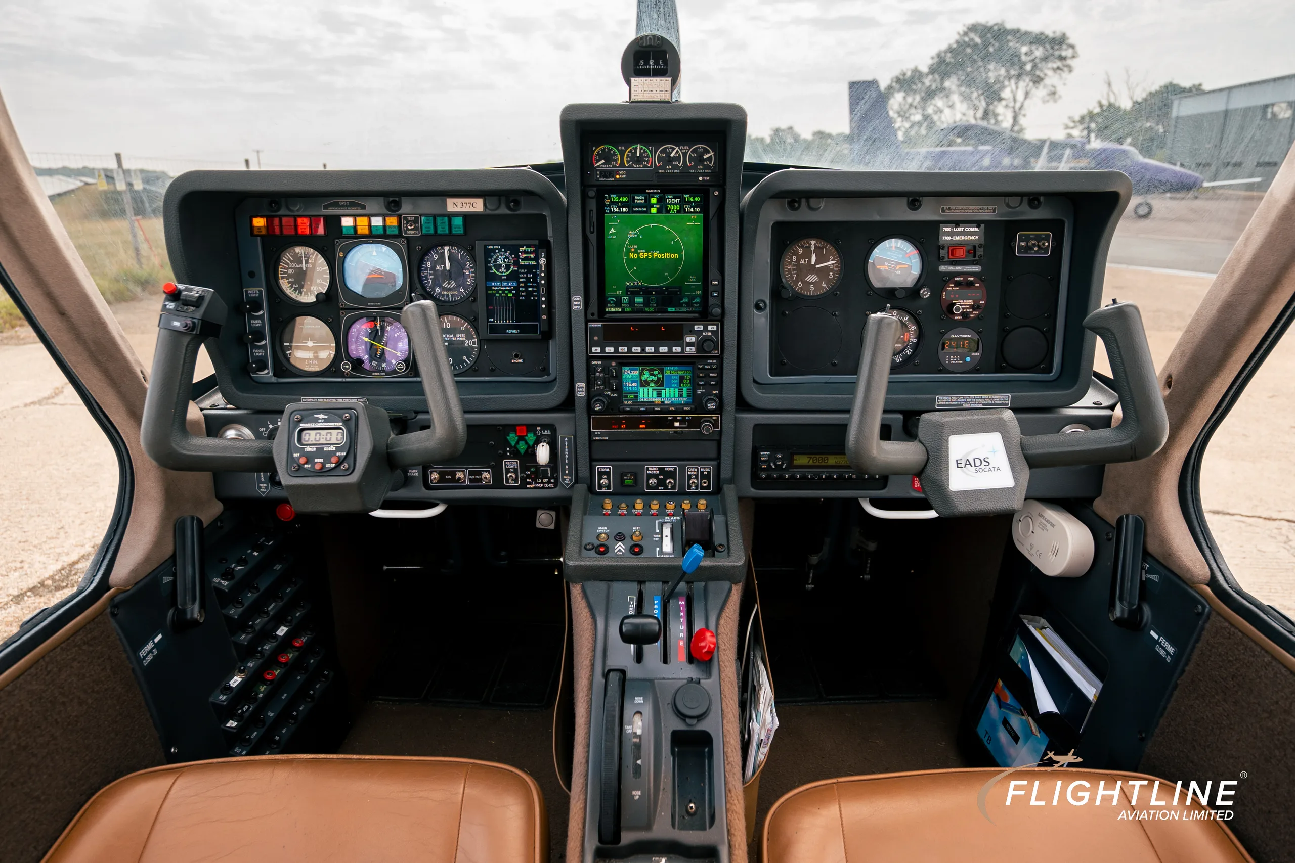 The cockpit of the N377C Socata Trinidad GT, featuring a modern glass panel display flanked by traditional gauges and dual yokes.