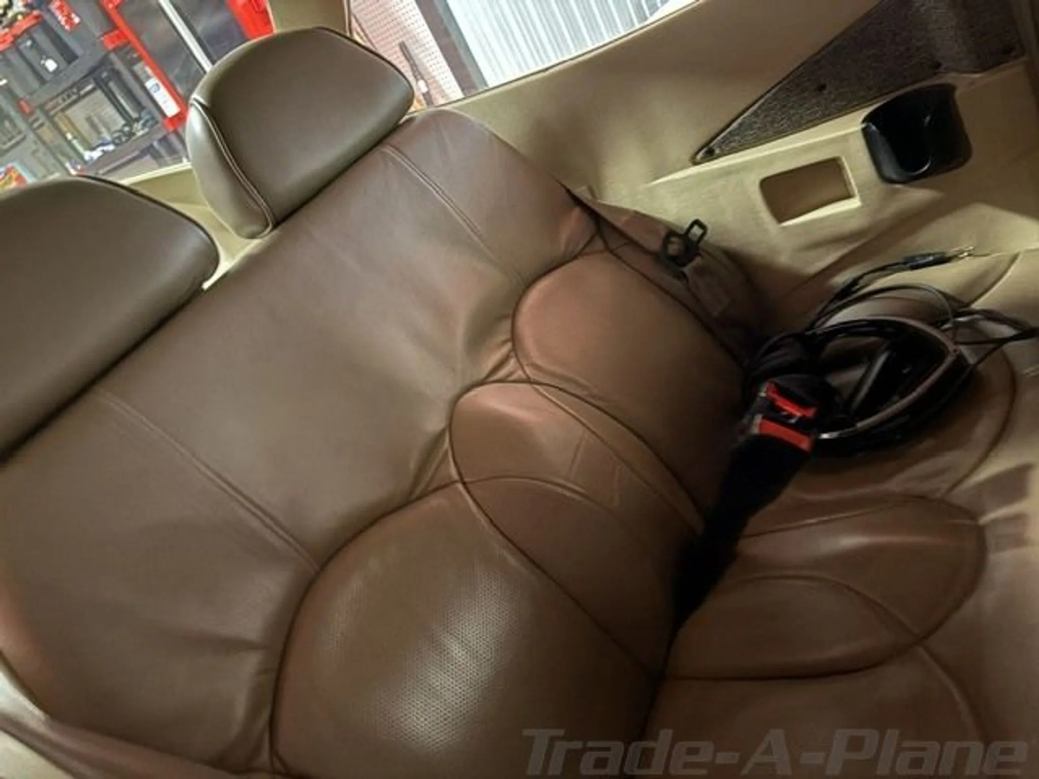 The tan leather rear seats of a small aircraft cabin.
