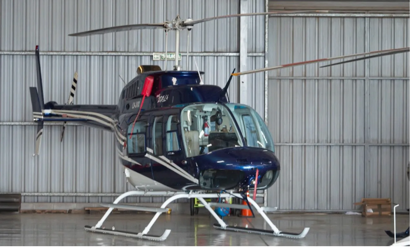 A blue Bell 206L-4 helicopter inside a hangar.