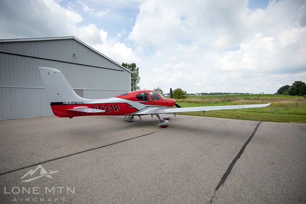 A red and silver Cirrus SR22 aircraft, N521P, seen from the rear-left, parked on an asphalt ramp.