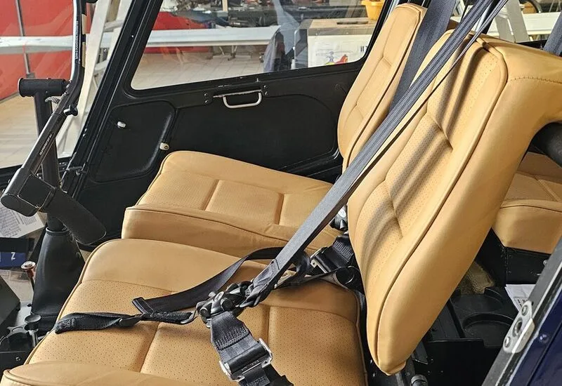 Close-up of the tan leather seats and seatbelts inside the helicopter cabin.