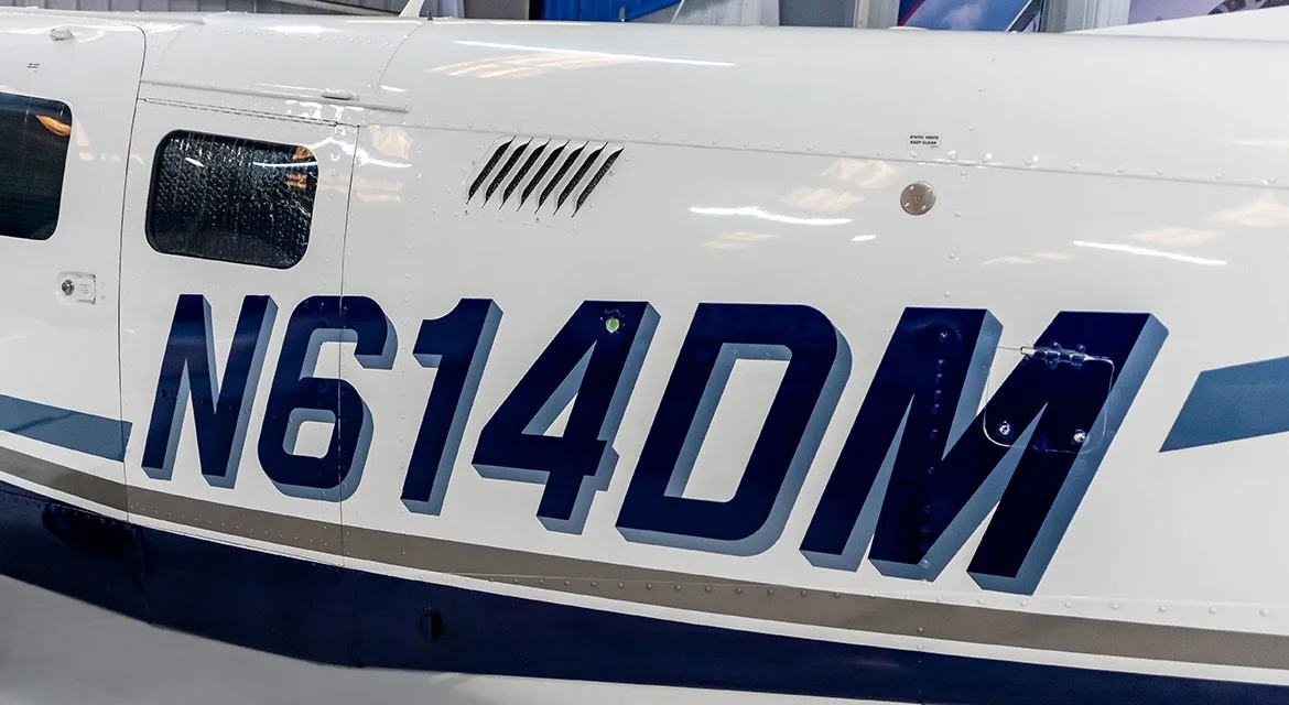 A close-up of the fuselage showing the registration N614DM on a white and blue aircraft.