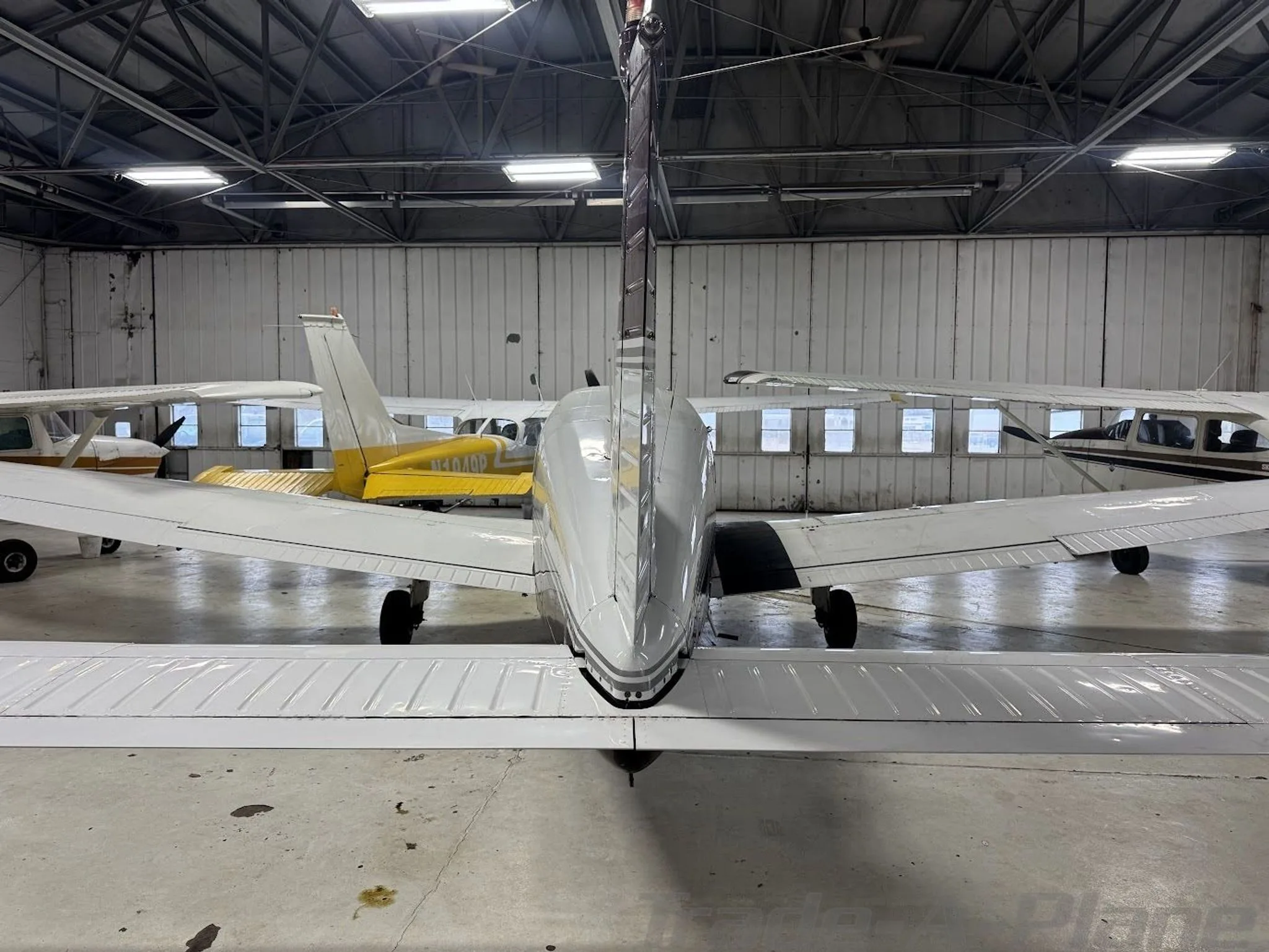 Rear view of a white and maroon Piper Archer II (N8150A) parked in a hangar.