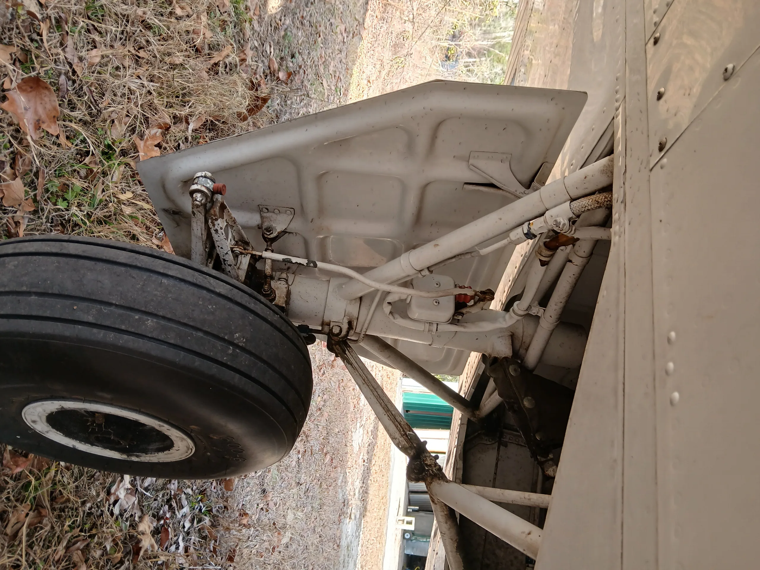 A close-up view of the white main landing gear and wheel of an aircraft.
