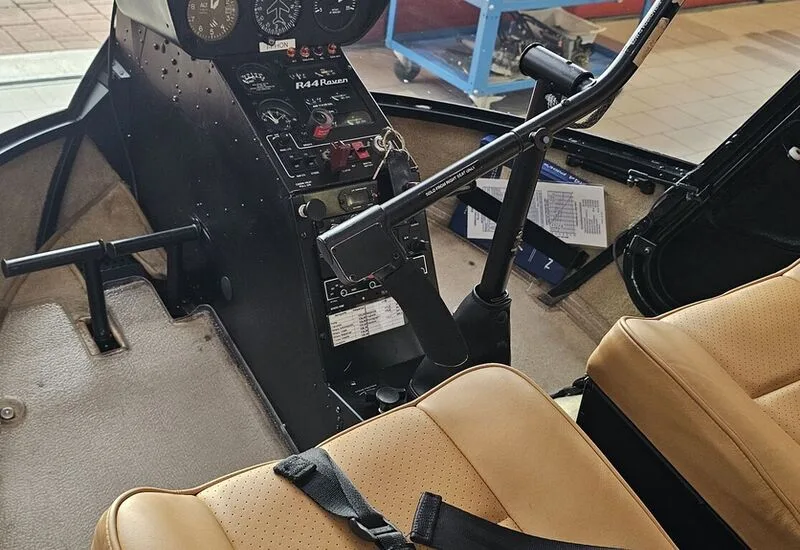 View of the helicopter cockpit with instrument panel and tan leather seats.
