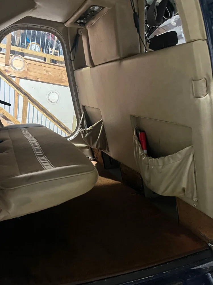 The tan interior cabin of a helicopter features rear seats with storage pockets.