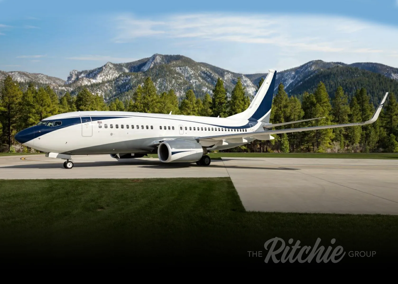 A luxurious aircraft cabin with light-colored sofas, chairs, and wooden tables.