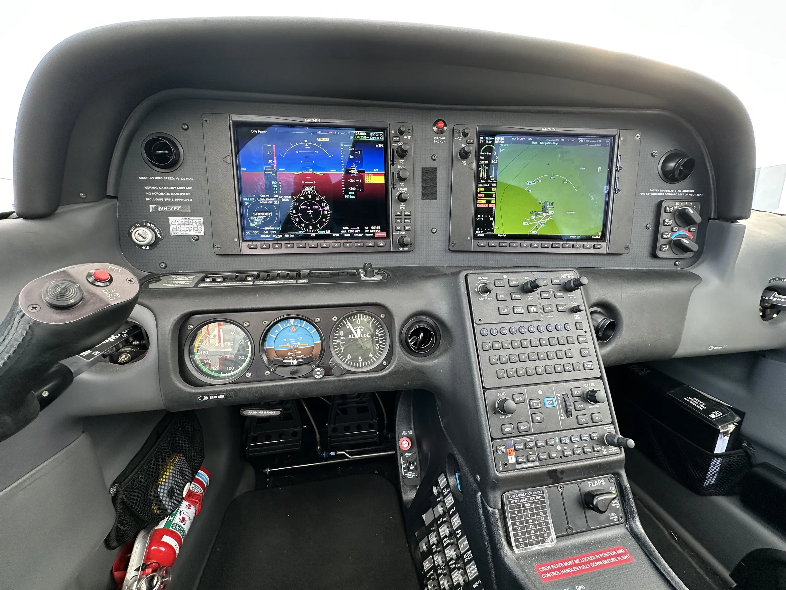 The cockpit of a modern aircraft featuring two large glass displays, traditional gauges, and a control yoke.
