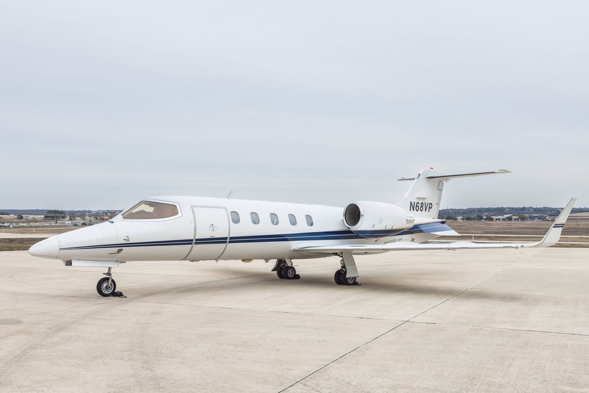 A white Learjet 45 with blue stripes and tail number N68VP parked on the tarmac.