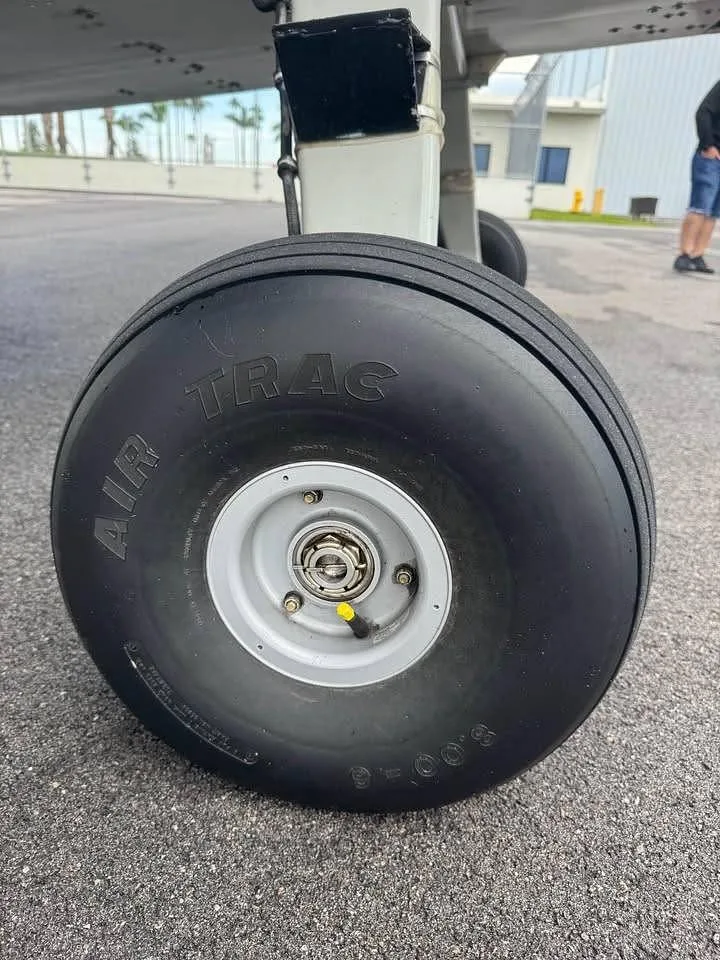 A close-up view of the main landing gear wheel with an "AIR TRAC" tire on a tarmac.
