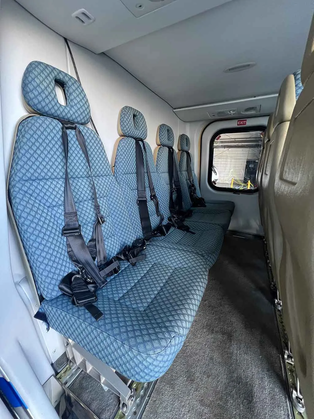 A view of the helicopter's interior cabin showing a long bench of blue patterned seats with harnesses.