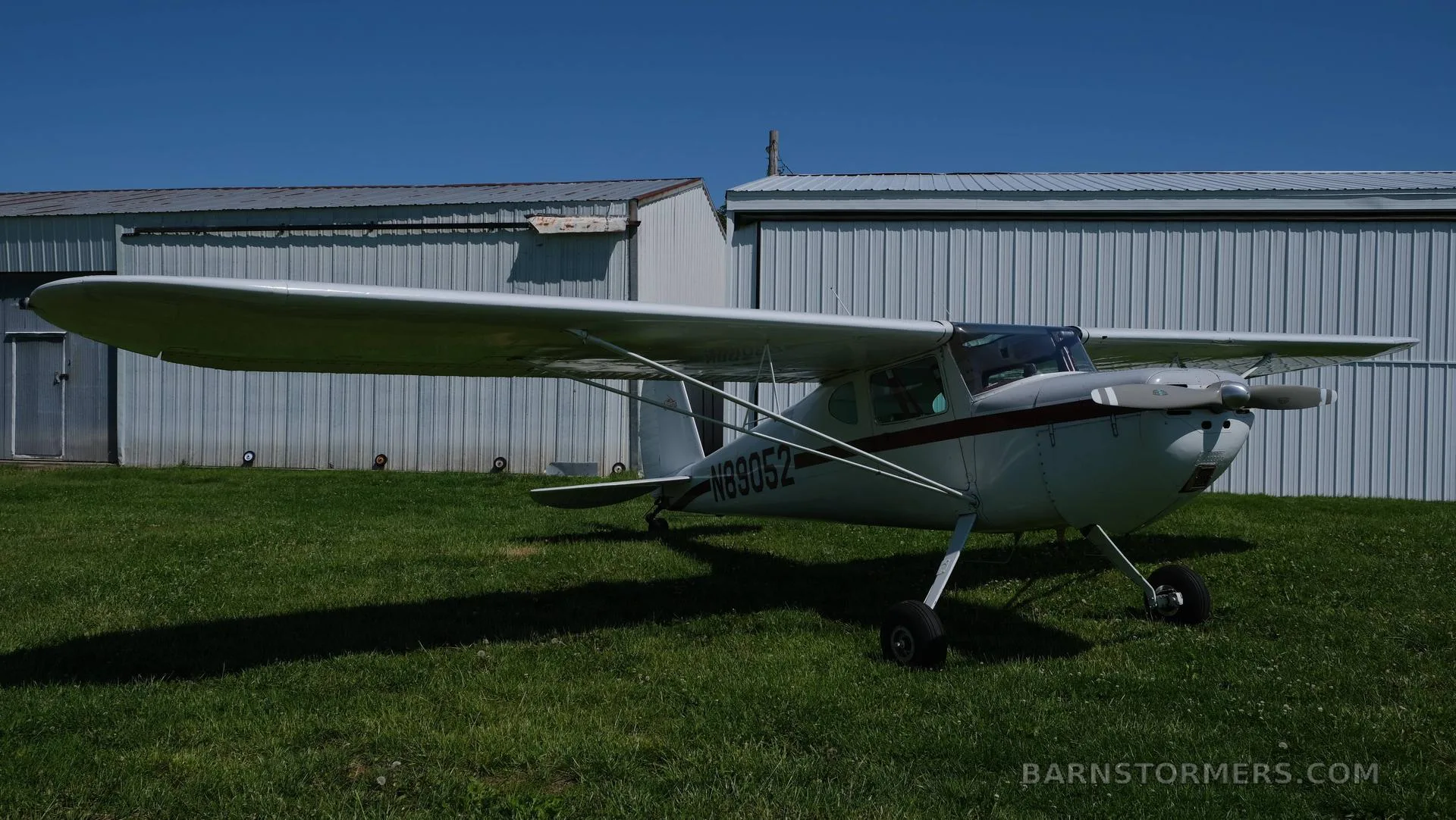 The interior of a small aircraft cabin with brown seats and red Hooker Harness seatbelts.