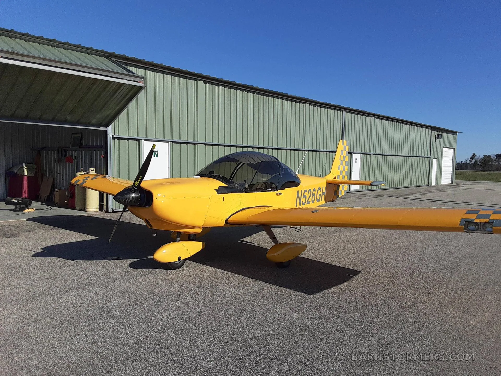 A yellow single-engine aircraft's cockpit and cabin interior with black and grey seats, an instrument panel, and an iPad mounted.