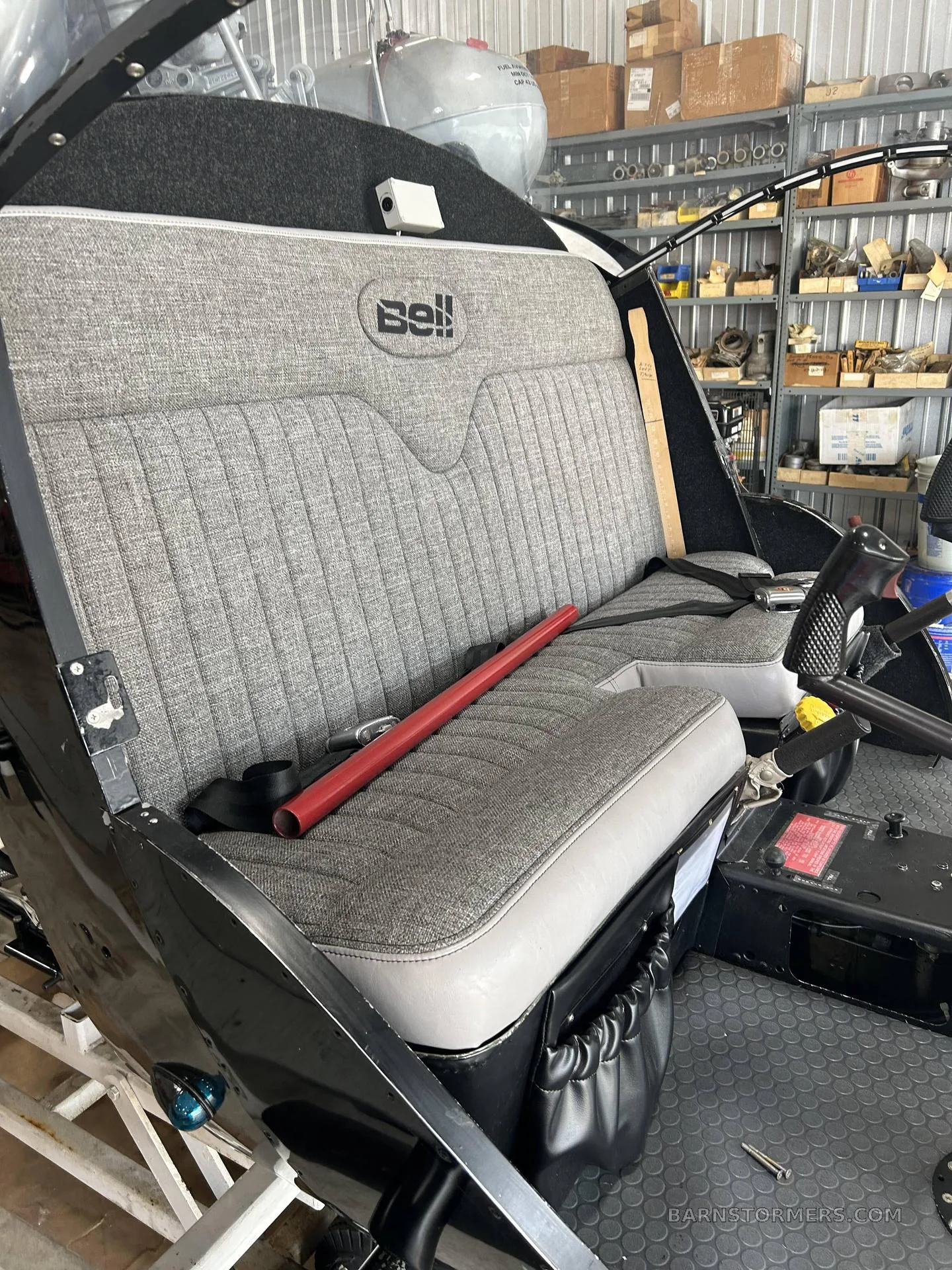 The grey fabric bench seat with a "Bell" logo inside a helicopter cabin.