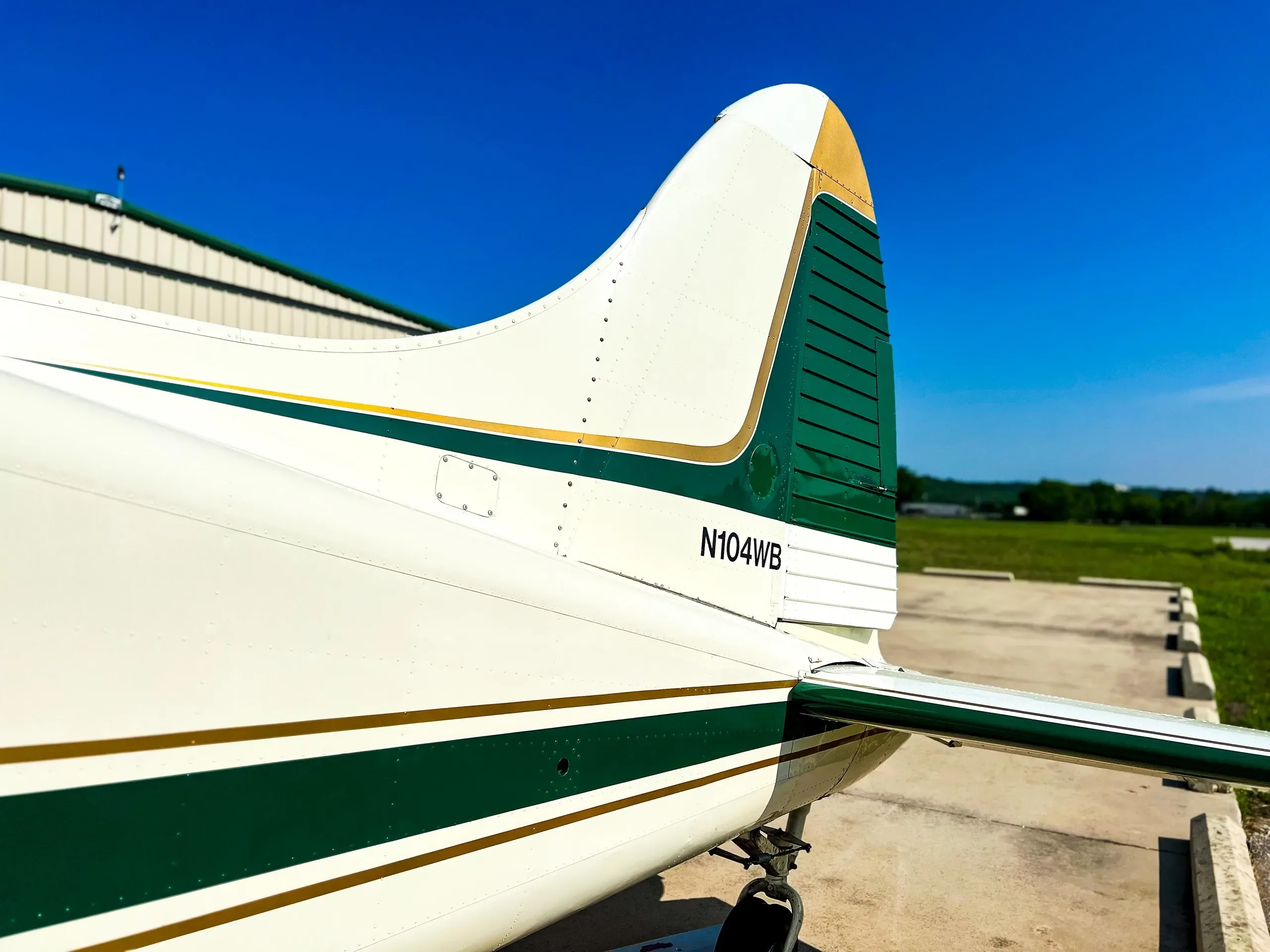 Close-up of the N104WB aircraft's tail, featuring green and gold stripes against a white fuselage.