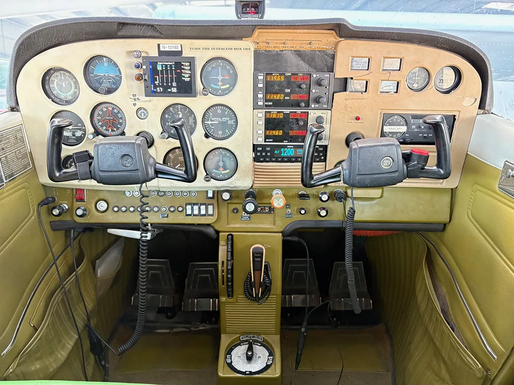 The cockpit of a Cessna 172 showing the instrument panel, yokes, and avionics.