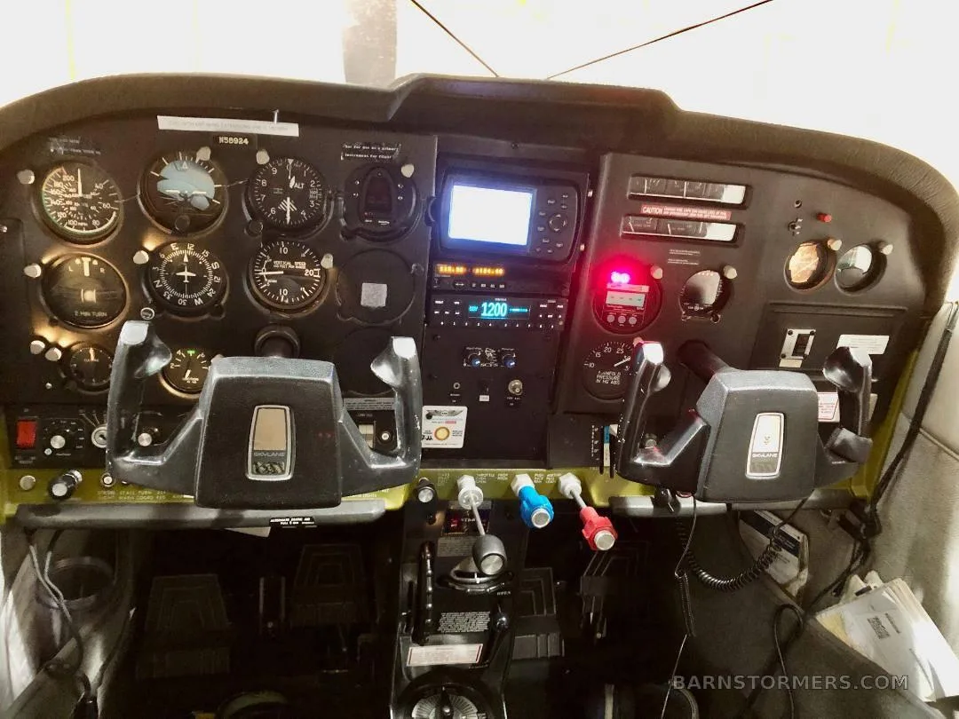 The cockpit of a Cessna 182 Skylane, showing the instrument panel, yokes, and avionics.